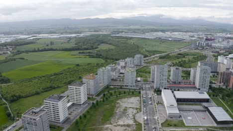 terreno montañoso con una ciudad moderna en el medio, campos verdes, nublado