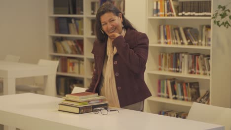 middle aged woman wearing jacket laughs in library