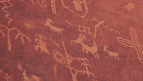 Ancient-petroglyphs-dating-back-thousands-of-years-on-red-weathered-sandstone-wall