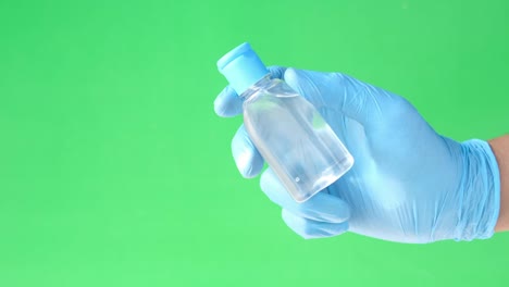 man hand in medical gloves holding sanitizer against green background