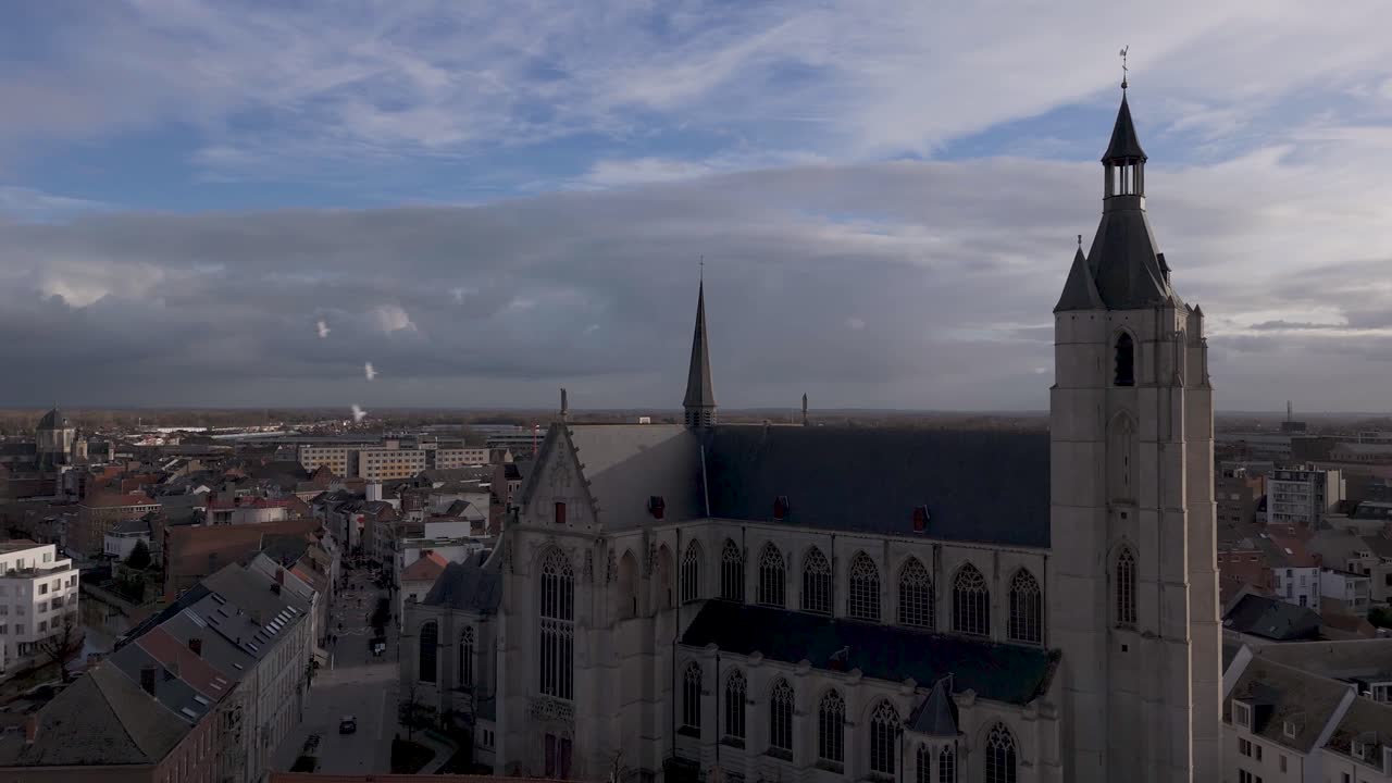 Drone shot of a church top in a city center while the sun hits the forefront of the church.