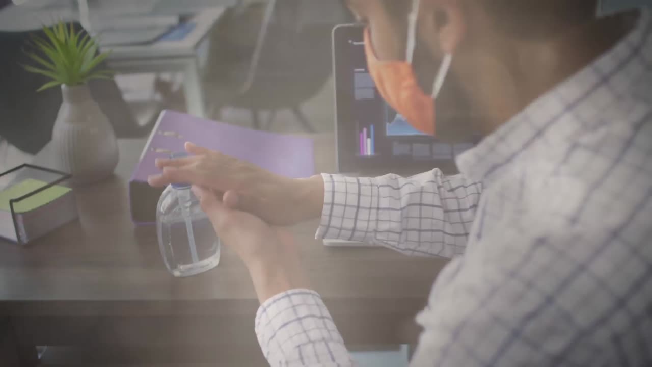 얼굴 마스크를 쓴 남자가 사무실에서 손을 소독하는 것에 대한 빛의 반점