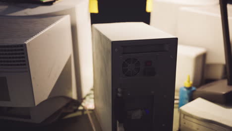 old computer equipment stacked on a desk in a dimly lit room