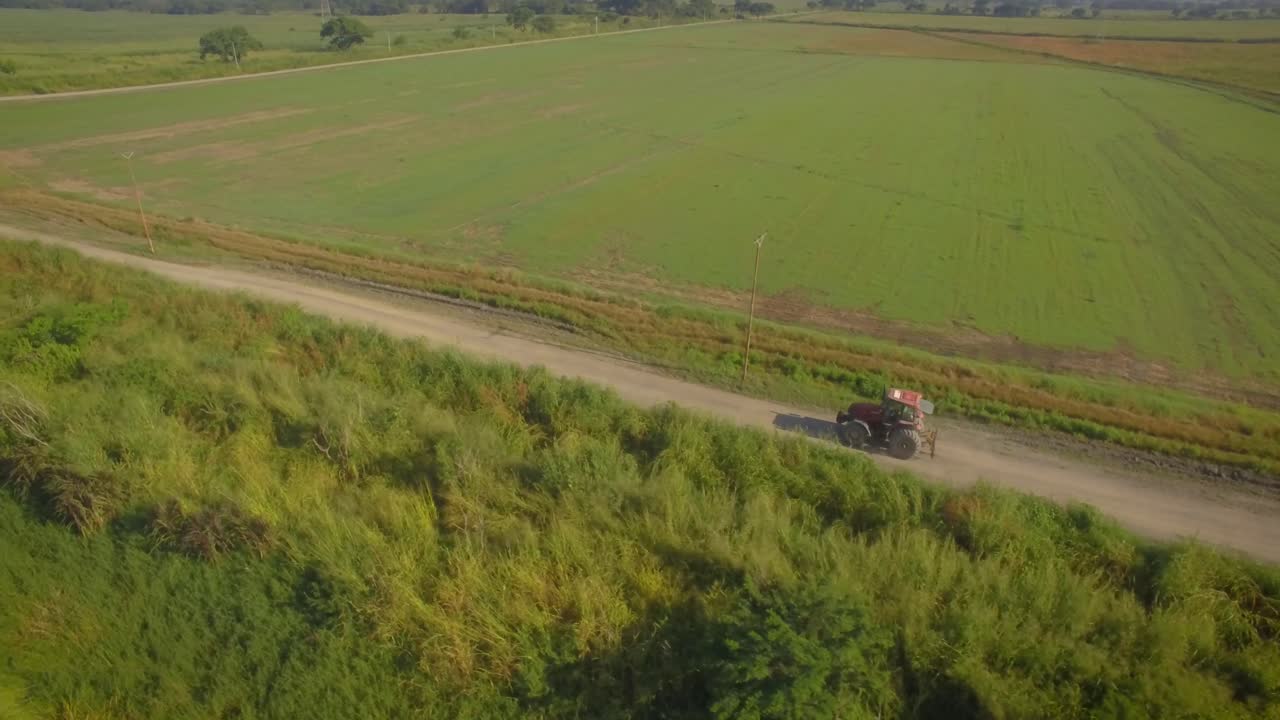 시골을 가로질러 비포장 도로를 달리는 트랙터의 공중 발사