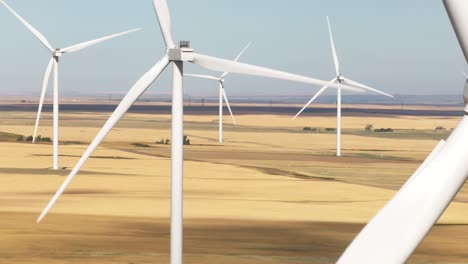 Static-aerial-view-of-the-giant-vanes-of-a-windmill-spinning-on-a-wind-farm-of-Southern-Alberta,-Canada