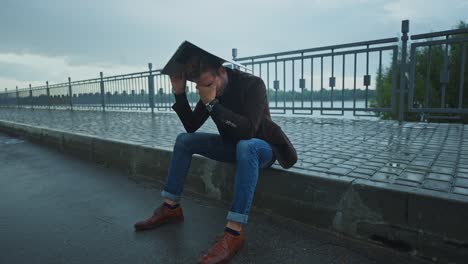 stressed man with laptop in the rain