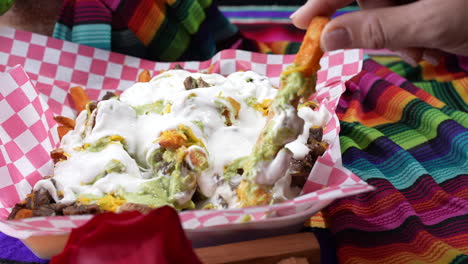 Person's-hand-seen-taking-gooey-carne-asada-fries---food-truck-series