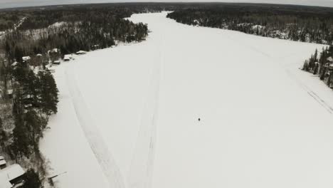 una moto de nieve viaja a lo largo de un lago congelado en el ártico de canadá