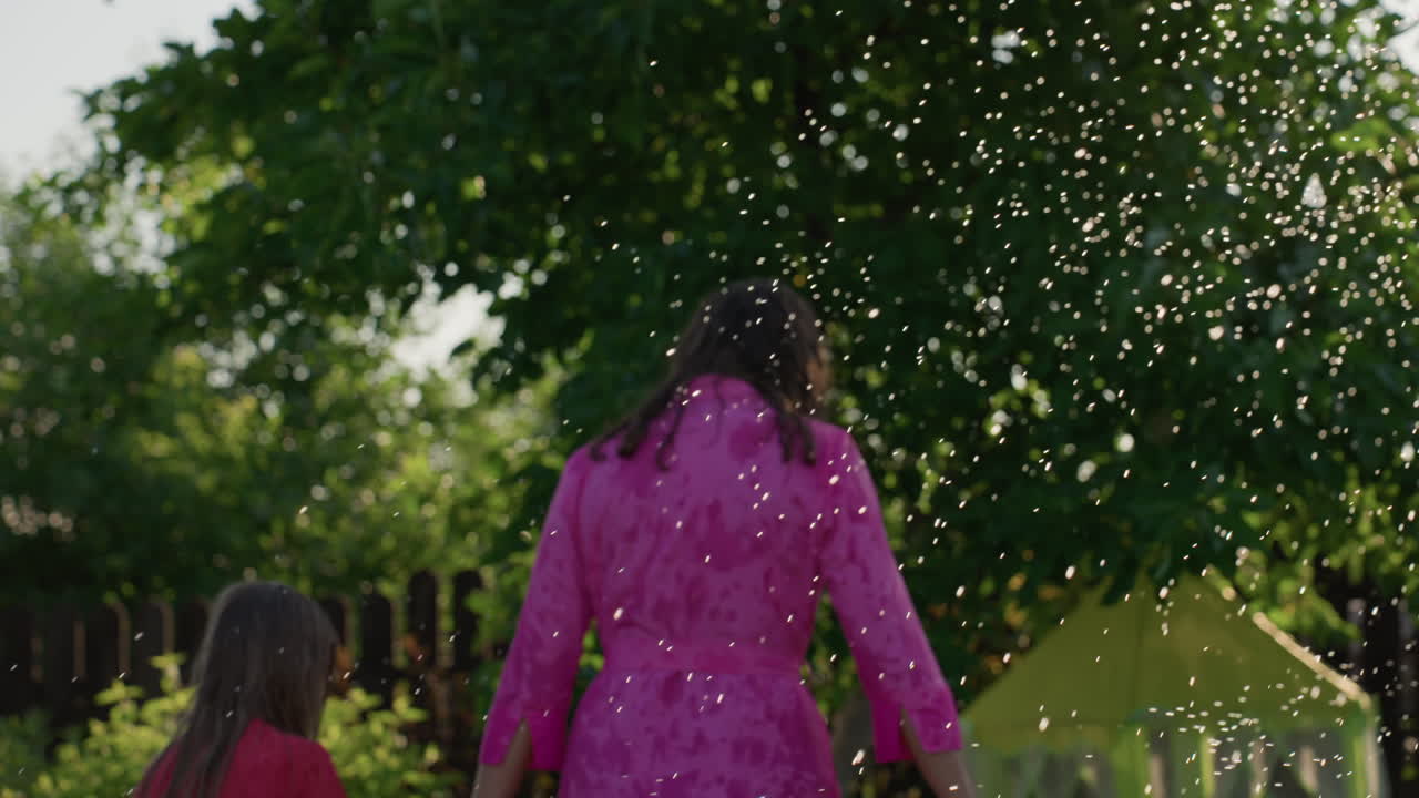 Mother Daughter Walk, Garden Scene With Water Spray, Sunlit Figures Sharing Gentle Summer Moments, Tender Mother And Daughter Strolling Through Misty Garden Ambiance Surrounded By Warmth