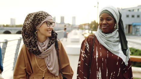 young muslim women walking on embankment