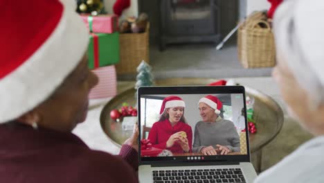 Smiling-diverse-senior-female-friends-using-laptop-for-christmas-video-call-with-family-on-screen