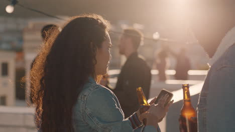 grupo de amigos pasando el rato juntos disfrutando de una fiesta en la azotea al atardecer tomando selfies usando teléfonos inteligentes bebiendo alcohol divirtiéndose el fin de semana compartiendo celebraciones