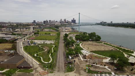 Construcción-De-Un-Parque-Junto-Al-Río-Con-El-Horizonte-De-Detroit-En-El-Horizonte,-Vista-Aérea