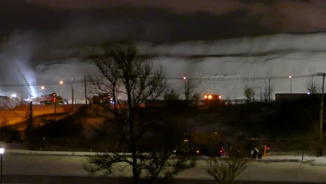 A-snow-clearing-operation-with-trucks-and-bulldozers-operating-in-the-dark-to-clear-the-snow-from-the-city-in-Montreal,-Canada