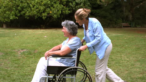 Mujer-Joven-Empujando-A-Su-Madre-En-Silla-De-Ruedas.-