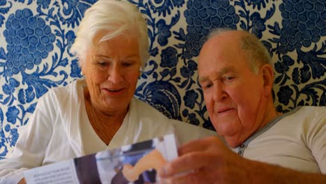 front view of caucasian senior couple reading news paper on bed in bedroom at comfortable home 4k