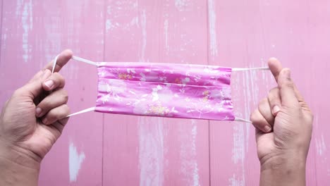 pink floral fabric mask in hands