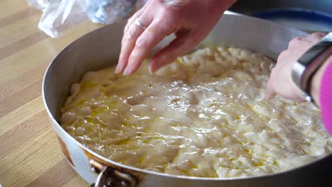 spreading focaccia dough into metal pan - homemade baking 60fps