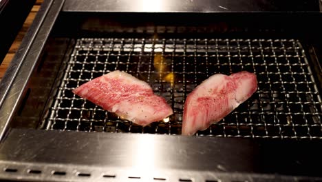 steak pieces cooking on a grill, changing color