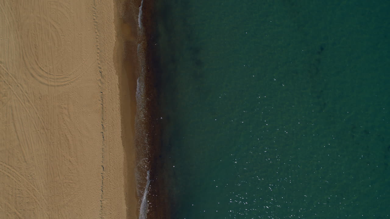 Tranquilla vista di spiaggia sabbiosa con superficie dell'oceano calma in una calda mattina di sole.