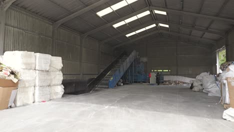 dolly forward into paper recycling center facility with conveyor belt, other equipment