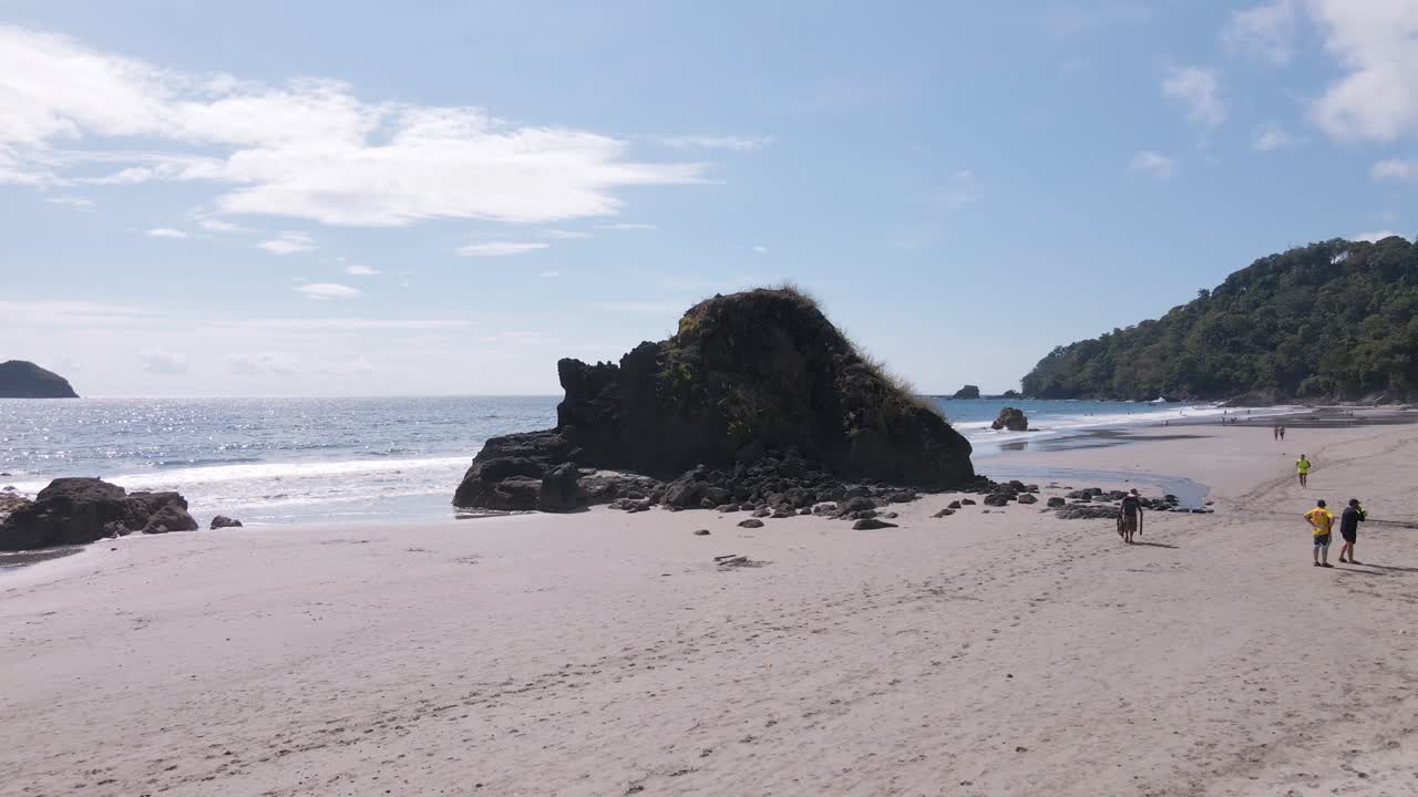 drone aéreo disparado en una playa de arena blanca que se eleva sobre una roca hacia el océano