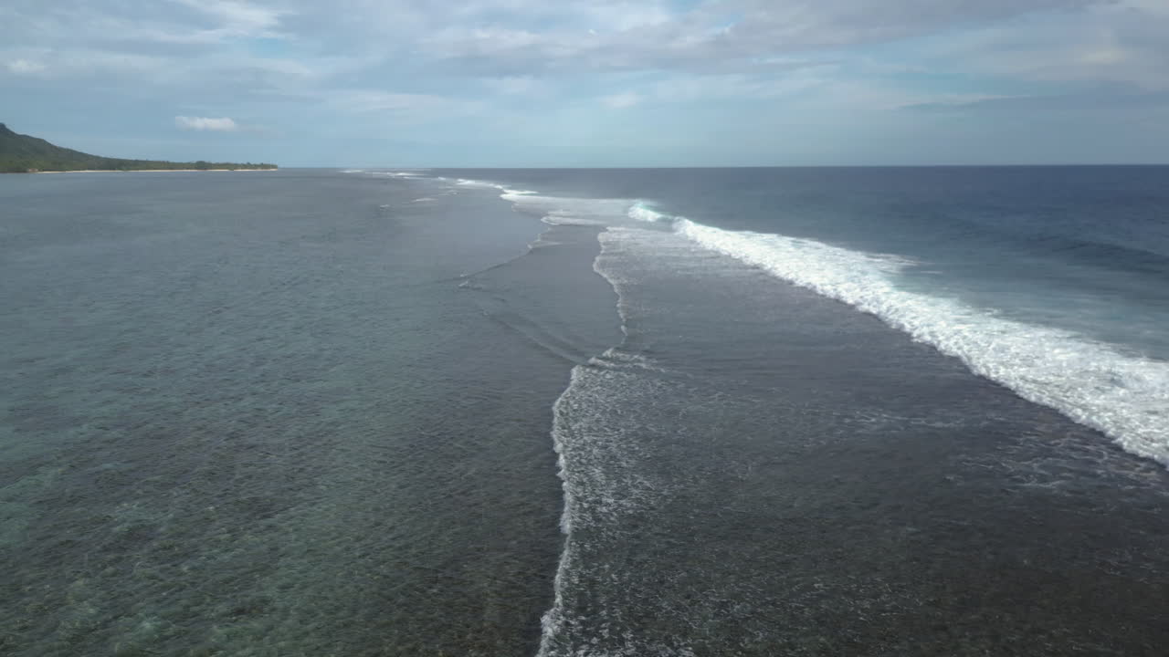Panoramic overview of waves breaking on shallow fringing reef in ocean water