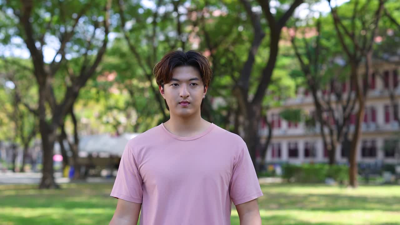 Một chàng trai trẻ người Thái đặt tay lên ngực với vẻ ngạc nhiên và biết ơn khi ở ngoài trời