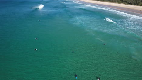 Surfistas-Flotando-En-El-Mar-En-La-Playa-De-Sol,-Queensland,-Australia---Toma-Aérea
