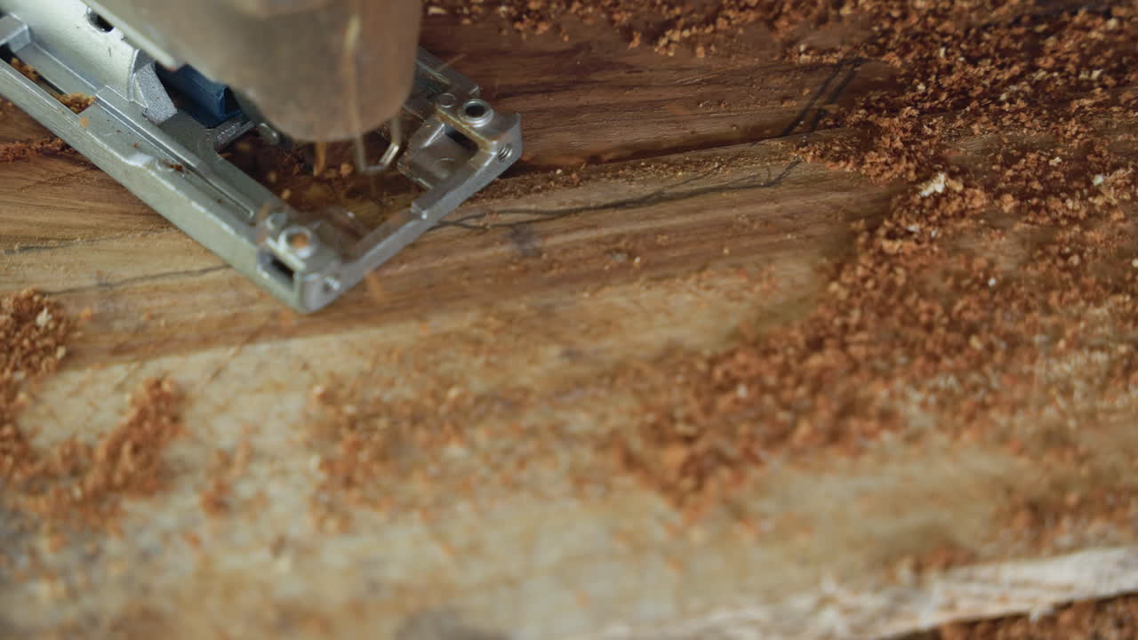Jigsaw cutting oak plank closeup, meticulous carpentry detail with fine sawdust and narrow groove, steady blade guiding through grain on workshop bench, hobbyist cabinetmaker trimming edge