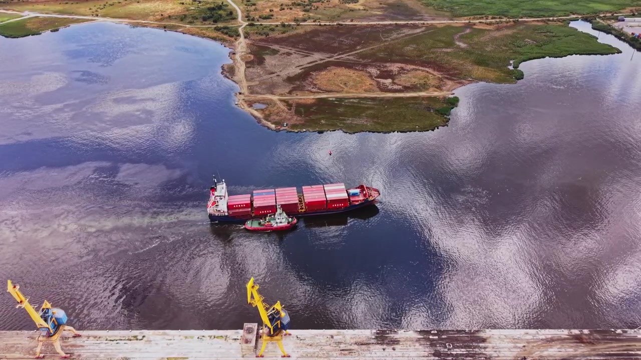 Nave mercantile che naviga un fiume vicino a un paesaggio verde sotto un cielo blu