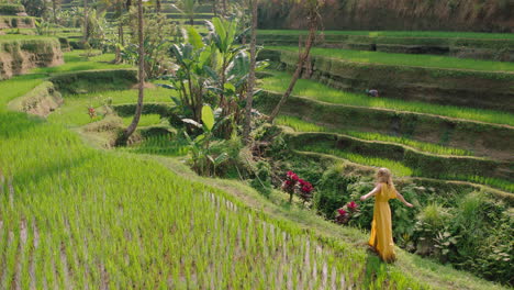 happy woman walking in rice paddy wearing yellow dress enjoying vacation exploring exotic cultural landscape travel through bali indonesia