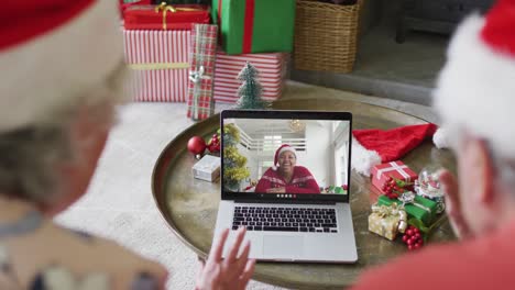 Caucasian-senior-couple-with-santa-hats-using-laptop-for-christmas-video-call-with-woman-on-screen