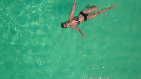 Woman-floating-in-calm,-warm,-tropical-ocean.-AERIAL