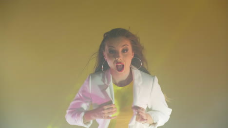 an energetic positive woman joyfully dances on a yellow background in the studio and screams while looking at the camera. success and joy. the concept of happiness.