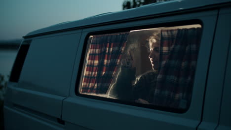 Woman-Drawing-on-Window-of-Camper-Van-and-Closing-Curtains