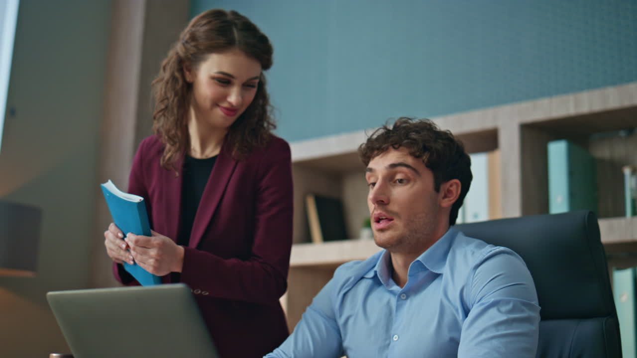 Woman mentor checking work man trainee in corporate office. Couple colleagues