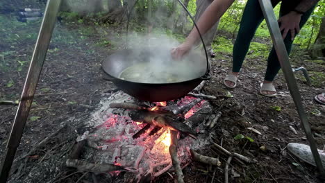 steaming, boiling soup over a campfire - taste with a spoon