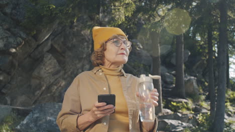 mujer mayor usando el teléfono en la naturaleza