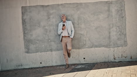 man leaning against a concrete wall using a smartphone