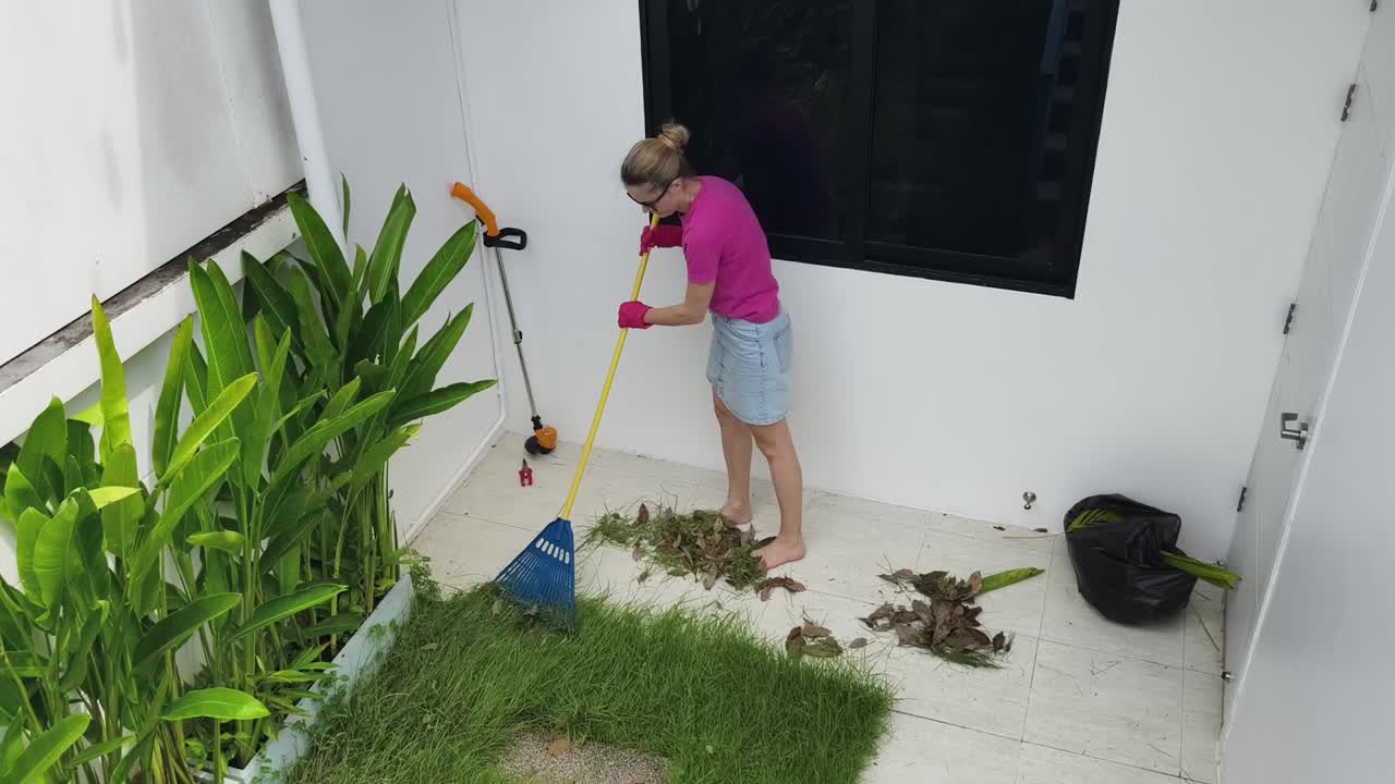 mujer rastrillando hojas en un patio del patio
