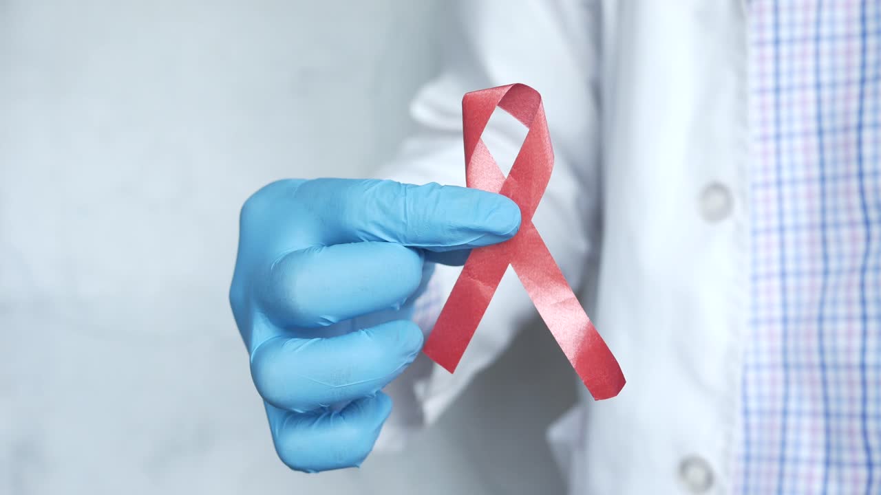médico sosteniendo una cinta de conciencia roja
