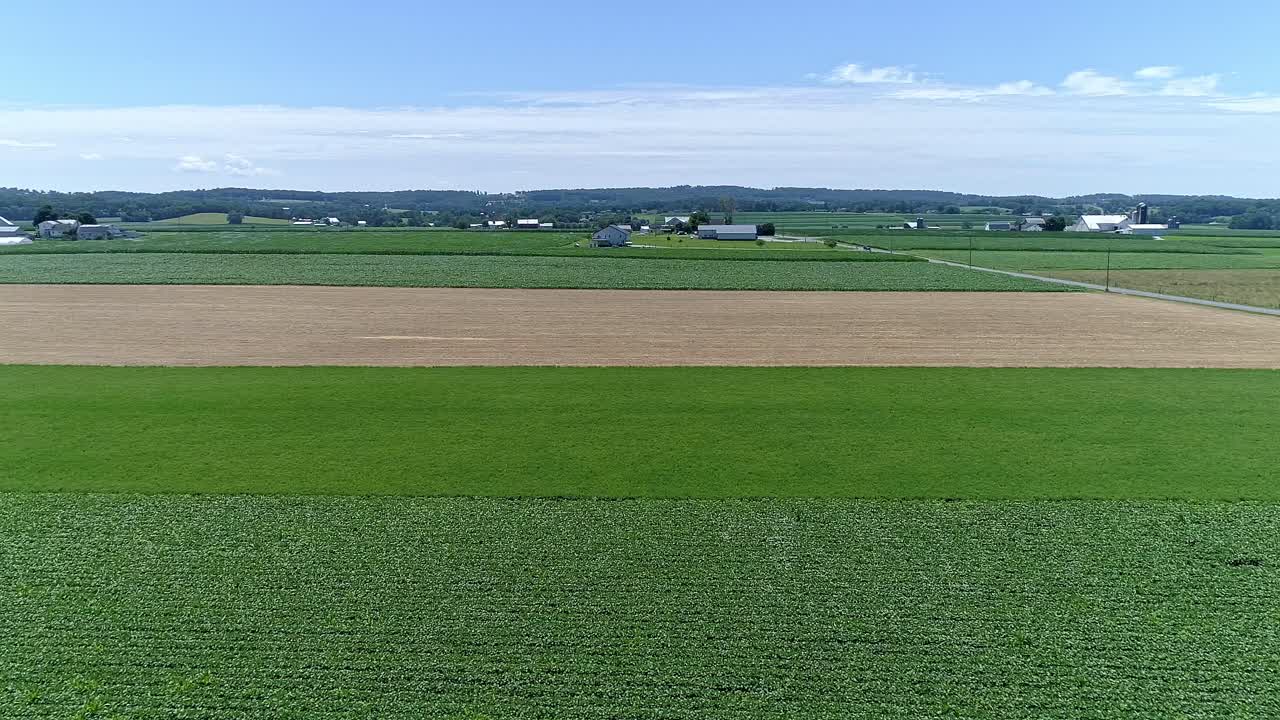 The landscape showcases expansive green fields interspersed with golden patches