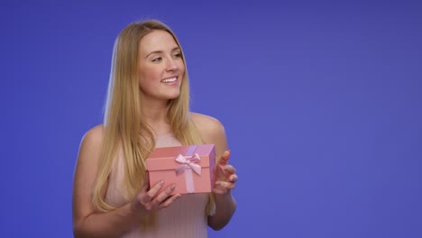 hermosa mujer joven está sosteniendo una caja de regalos en sus manos en pantalla azul