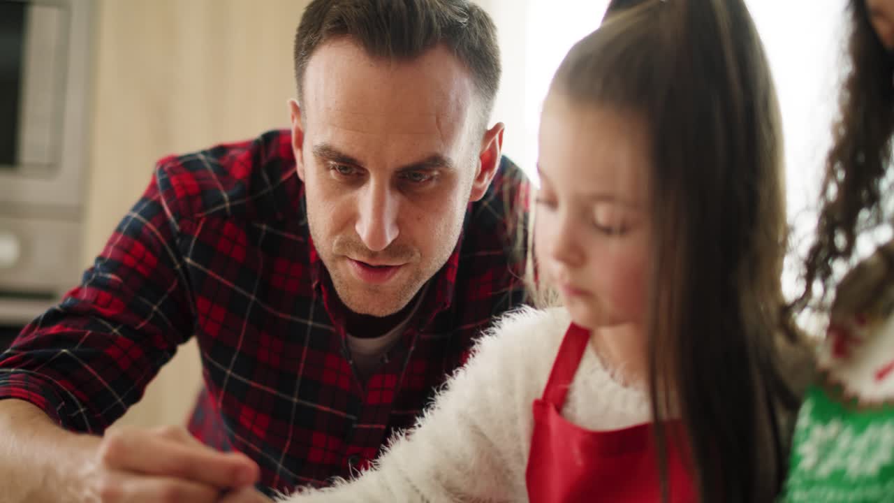 vista de mano de papá y su pequeña hija decorando galletas