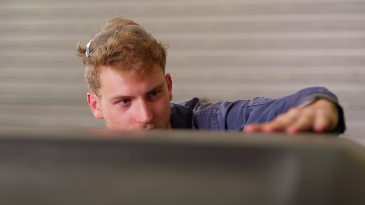 blonder handwerker in einer werkstatt in der garage, der ein metallprojekt inspiziert, 4k