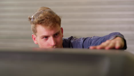 blonde tradesman in garage workshop inspecting metal project, 4k