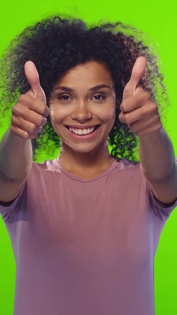 Giovane donna afroamericana gioiosa sorride ampiamente e mostra sicurezza.