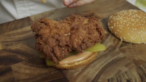 el chef pone capas de carne de pollo y queso encima del pan de hamburguesa