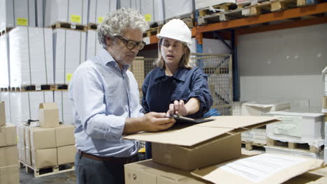 serious bearded boss talking with female worker using tablet